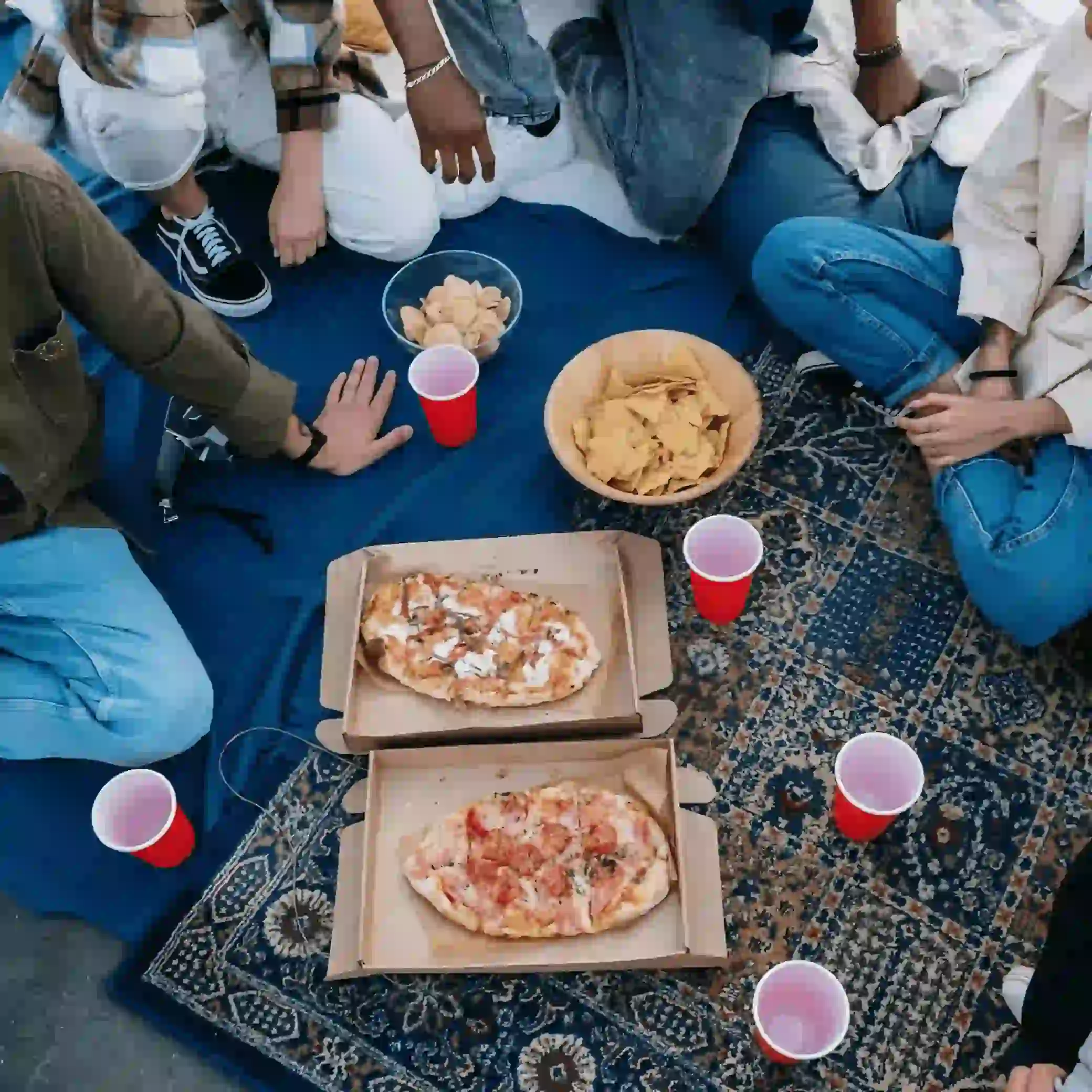 Enjoying delicious pizza with snacks and drinks alongside friends in the park.