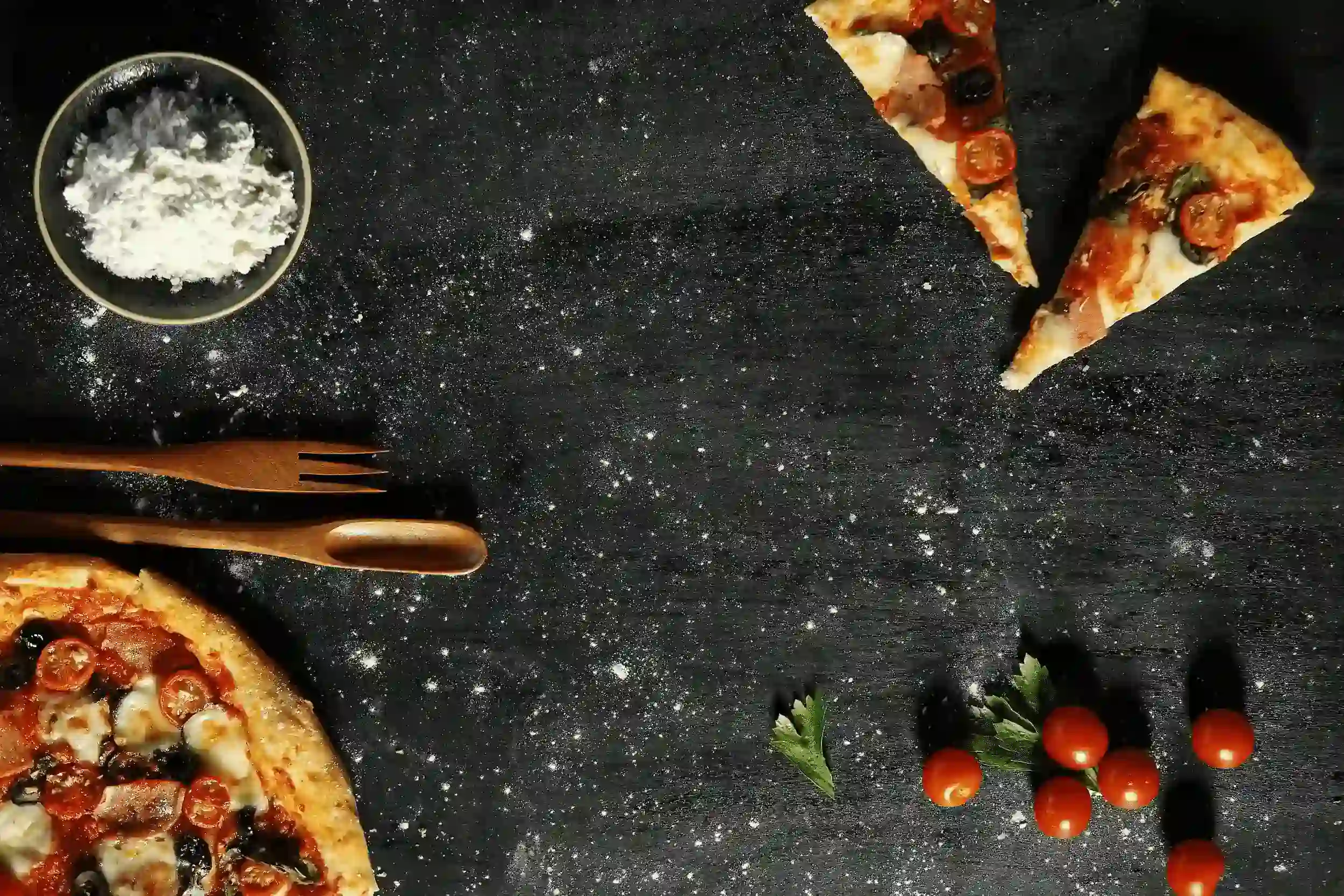 Pizza preparation station with fresh vegetarian slices, vegetables and pizza dough dust.