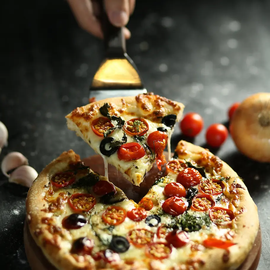 Simple vegetarian pizza inspired by the history of pizza topped with cheese, olives, tomatoes and garnishes.